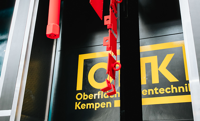 Rote Metallobjekte hängen vor OTK Logo